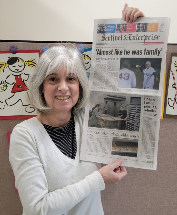 Deborah O'Kelly holding front page of Fitchburg Sentinel and Enterprise paper