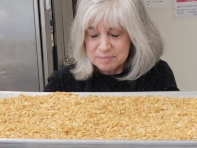 Deborah O'Kelly smelling freshly baked granola on tray