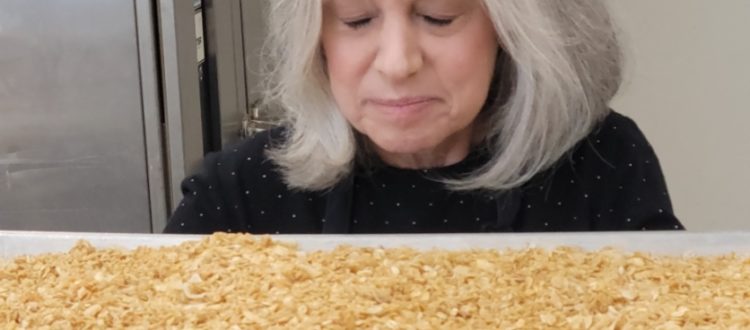 Deborah O'Kelly smelling freshly baked granola on tray